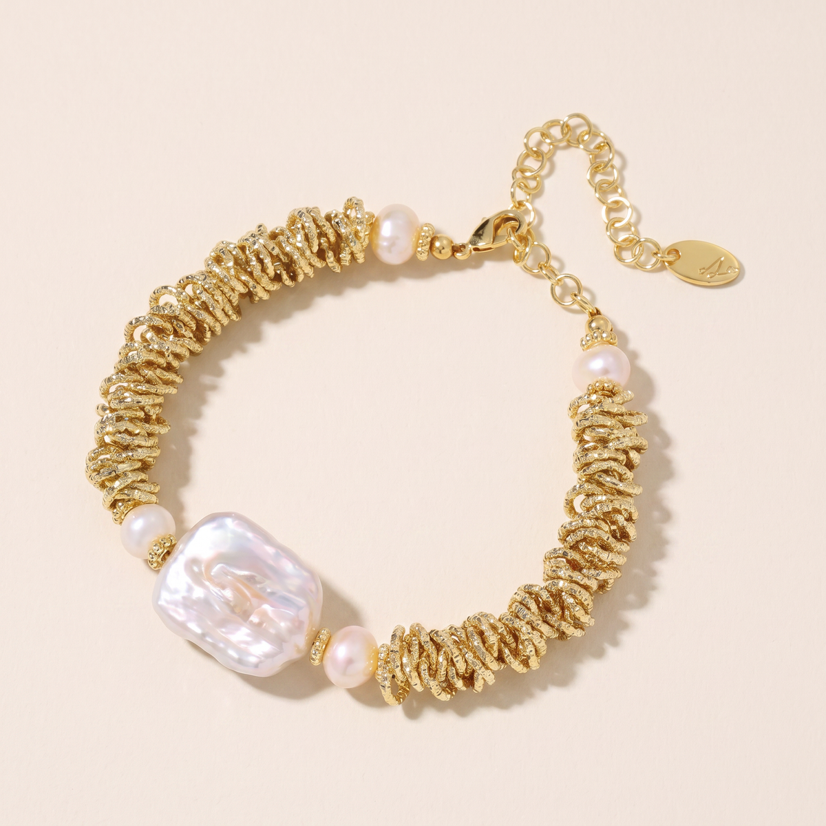 Deep Current bracelet laid flat, textured gold links with freshwater pearls and a large baroque pearl