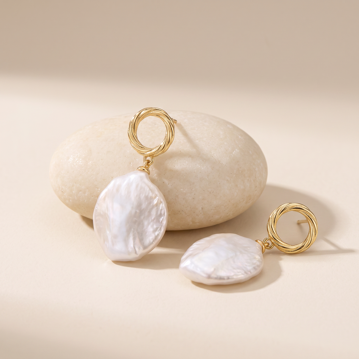 First Tide earrings resting on a pale stone