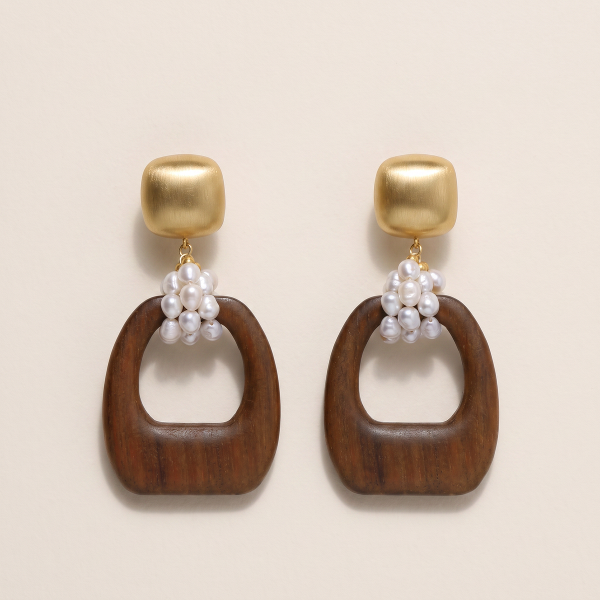 Heartwood earrings, the pair laid flat, brushed gold stud with pearl cluster and carved wood ring