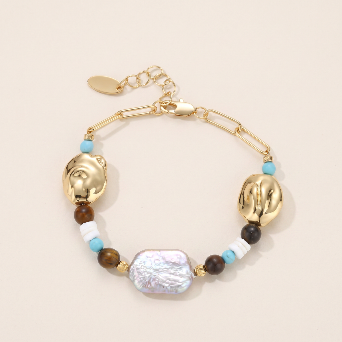 Compass bracelet laid flat, turquoise, tiger's eye and white shell with a baroque pearl on gold chain