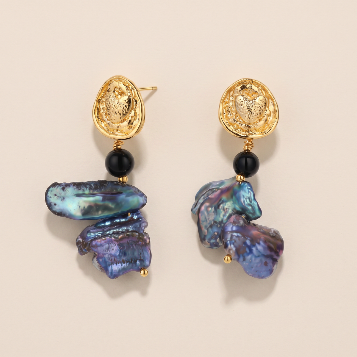 Deepwater Pearl earrings, the pair laid flat, hammered gold stud with onyx and peacock baroque pearls