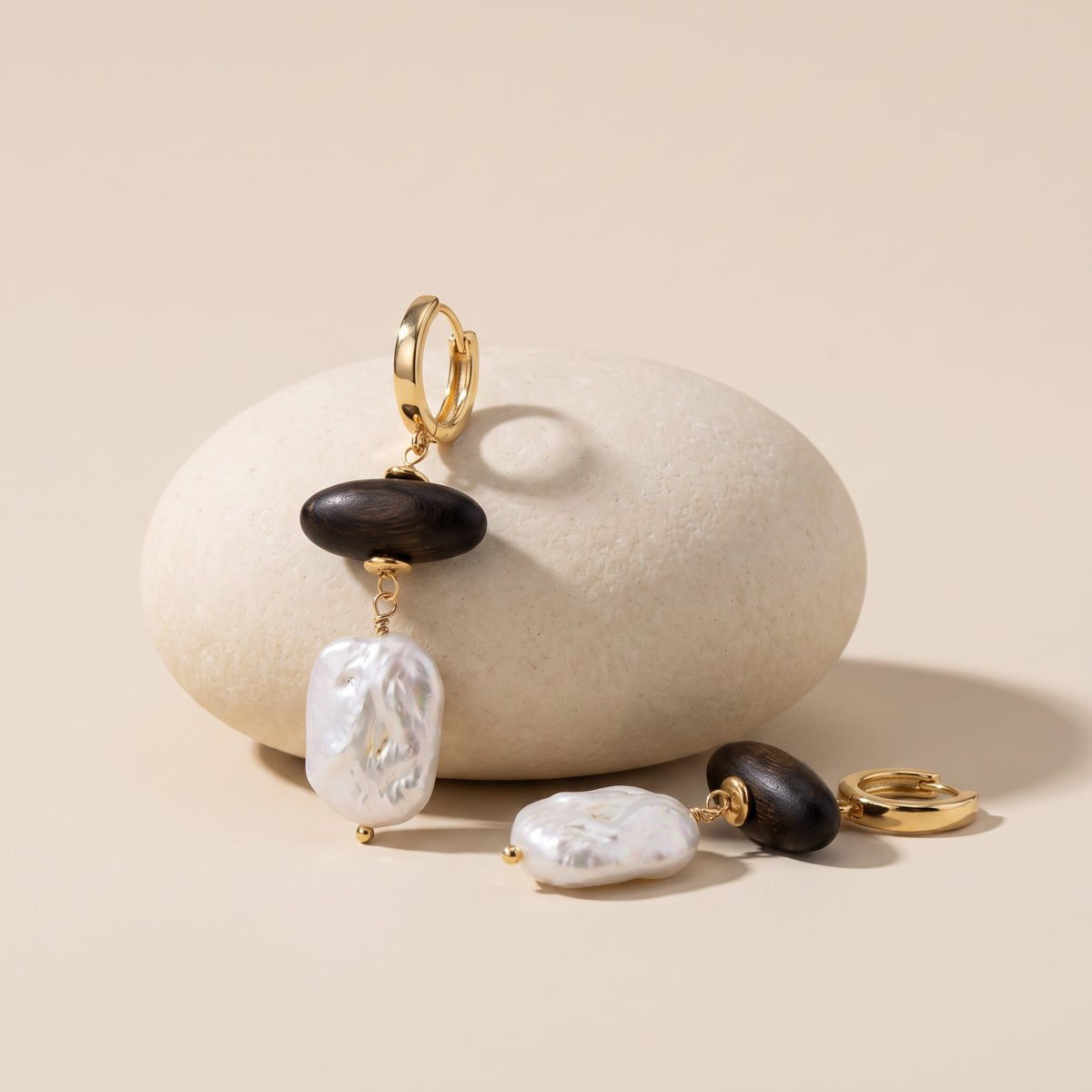 Grounded earrings resting on a pale stone