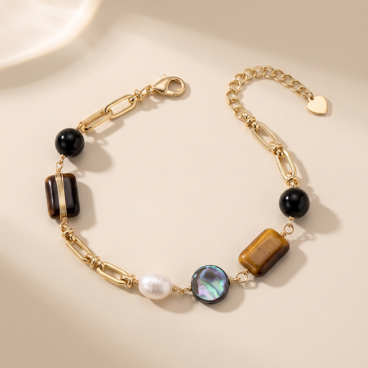 Obsidian Hour bracelet laid flat, obsidian and tiger's eye with freshwater pearl and abalone on gold chain