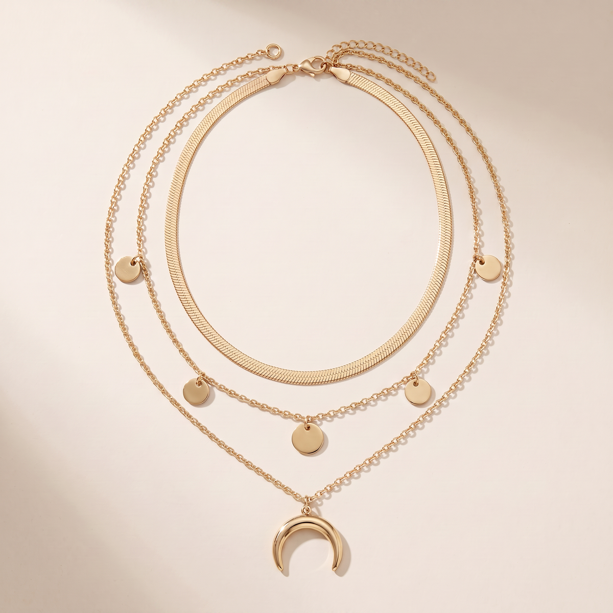 Three Moons necklace laid flat, herringbone chain, disc chain and crescent drop
