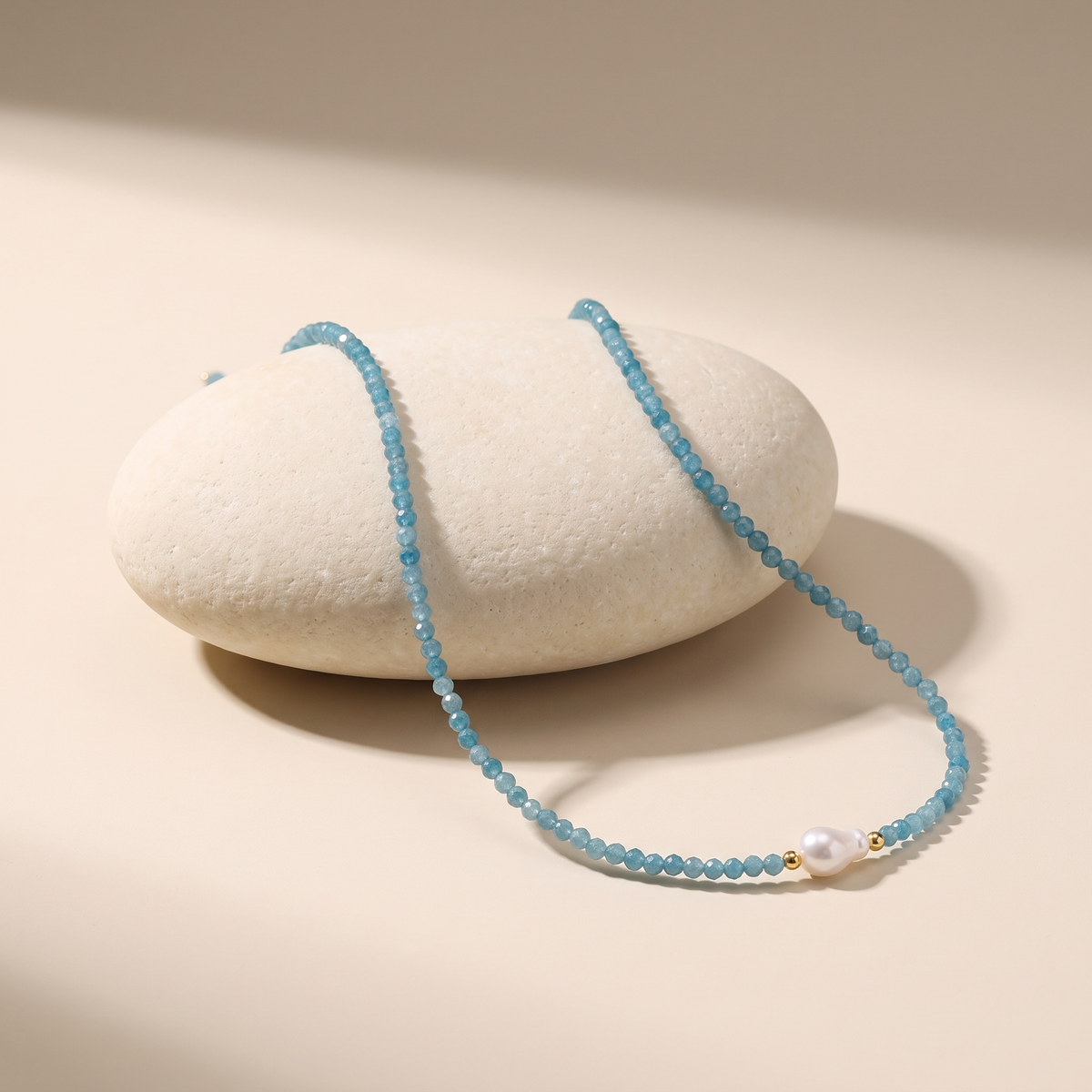 Tidewater necklace resting on a pale stone